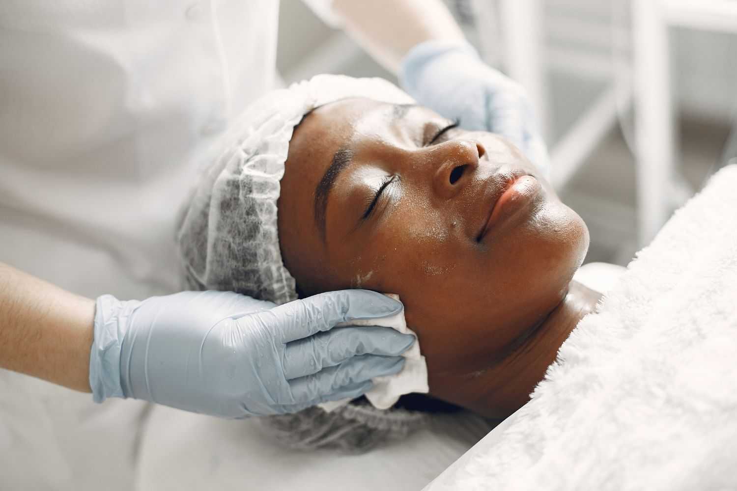 Person receives a relaxing facial treatment with cleansing cloth and gloves.